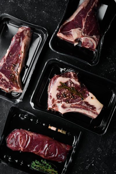 set-beef-steak-vacuum-packing-market-top-view-flat-lay-top-view-black-stone-cutting-table Set of beef steak in vacuum packing. Market. Top view. Flat lay top view on black stone cutting table.